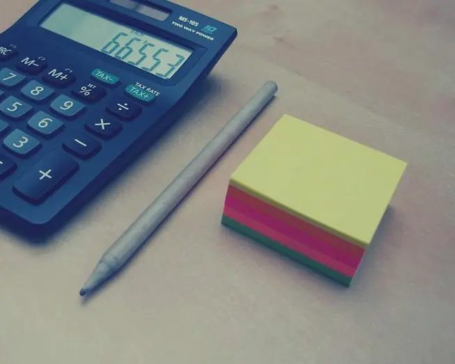 Calculadora, lápiz y bloc de notas de colores sobre una mesa