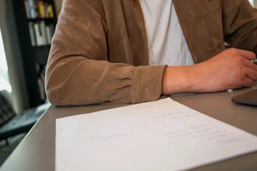 Persona sentada a una mesa revisando un documento impreso